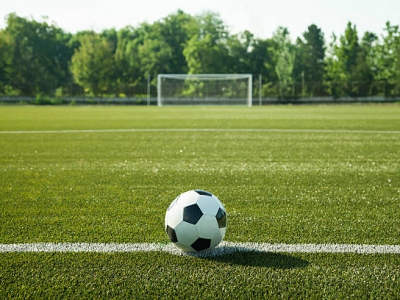 Soccer ball lying on the grass with the net of the goal as a backdrop